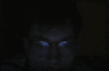 a close up of a person 's face in the dark with glasses on .