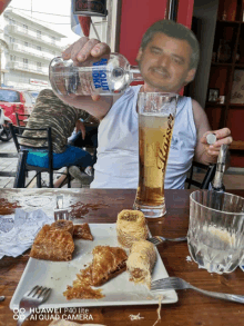 a man pours a bottle of aqua vodka into a glass of beer