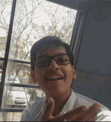 a boy wearing glasses and a white shirt is smiling for the camera