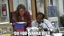 a man and a woman are sitting at a desk in an office with the words `` do you wanna die ? ''