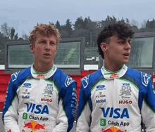 two young men wearing racing suits with visa cash app on them