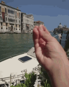 a person 's hand is reaching out towards the water in front of a sign that says ' italy ' on it