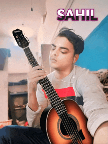 a man playing an acoustic guitar with the name sahil behind him