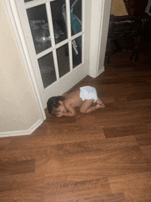 a baby in a diaper is laying on the floor in front of a door that says wilson