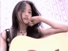 a woman with long black hair is holding a white guitar