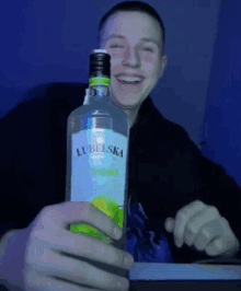 a man is holding a bottle of lubelska vodka in his hand