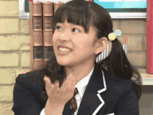 a girl in a school uniform is clapping her hands in front of a stack of books that say masters and apprentices