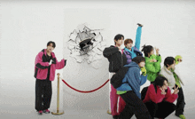 a group of young men are posing in front of a white wall with a hole in it