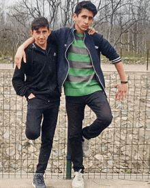 two young men posing for a picture with one wearing a green striped sweater