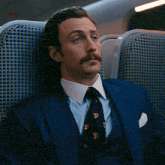 a man in a suit and tie is sitting in a chair
