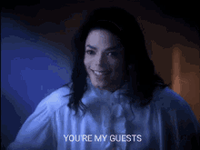 a man in a white shirt says " you 're my guests " in a dark room