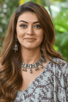 a woman wearing a necklace and earrings is smiling