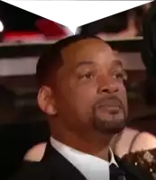 a man with a beard is wearing a suit and tie and sitting in a theatre .