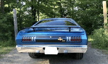 a blue car is parked on a gravel road