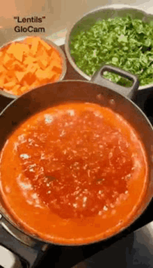 a pot of tomato sauce is being cooked in a pan on a stove next to bowls of vegetables .