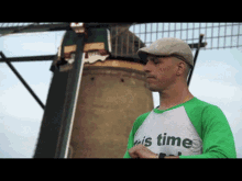 a man standing in front of a windmill wearing a shirt that says ' it 's time ' on it