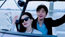 a man and a woman are sitting on a boat and the man is wearing sunglasses and the woman is wearing earrings