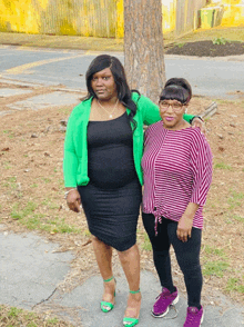 two women standing next to each other one wearing a green cardigan