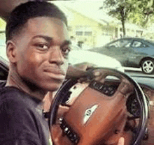 a young man is sitting in the driver 's seat of a bentley car .