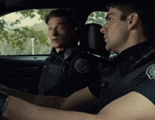 two police officers are sitting in a car and one of them has a patch on his chest that says ' a. '