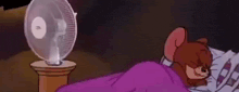 a cartoon mouse is sleeping in a bed with a fan in the background .