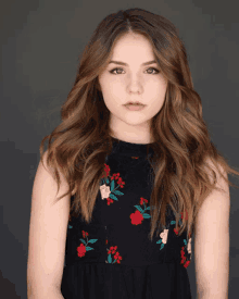 a young woman wearing a black dress with red and white flowers on it