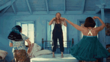 three women are jumping on a bed with one wearing a green dress