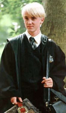 a young man in a harry potter costume is holding a briefcase .