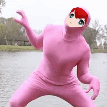 a person in a pink suit with a red haired girl on their face is standing next to a body of water .