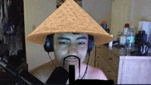 a man wearing a conical hat and headphones with a mustache is talking into a microphone .