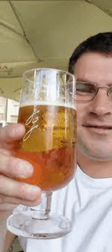 a man in glasses is holding a glass of beer .