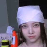 a woman wearing a white bandana and holding an orange cone is making a funny face .