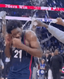 a basketball player with the number 21 on his jersey is sprayed with champagne