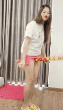 a woman in a white t-shirt and pink shorts is holding a hula hoop