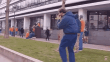 a man in a blue jacket is standing in front of a building taking a picture of a group of people .