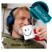 a man wearing headphones is drinking from a mug with a smiley face