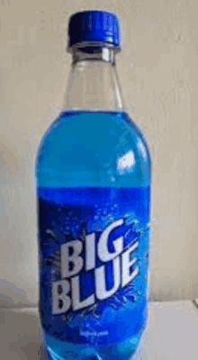 a bottle of big blue soda is sitting on top of a white table .