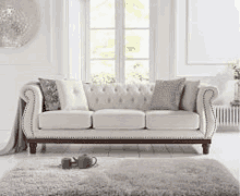 a white couch is sitting next to a window in a living room .