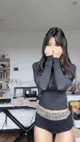 a woman covering her face with her hands while standing in front of a keyboard