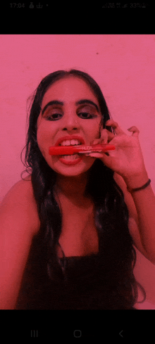 a woman brushing her teeth with a red brush