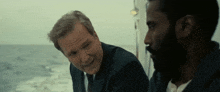 two men are sitting on a boat in the ocean and talking