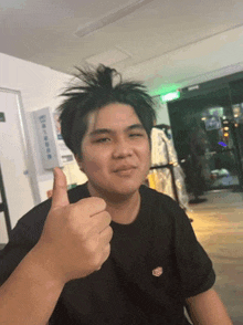 a man with messy hair is giving a thumbs up sign