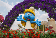 a smurf statue is surrounded by flowers and a castle