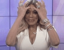 a woman is holding her head with her hands while wearing a white shirt .