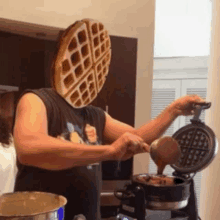 a man with a waffle on his head is pouring syrup on a waffle maker