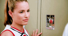a girl in a cheerleading uniform is standing in front of a locker with a padlock on it