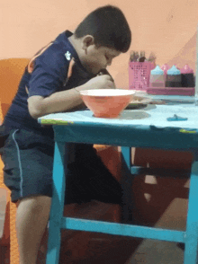 a boy sits at a table with a bowl of food