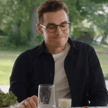 a man wearing glasses is sitting at a table