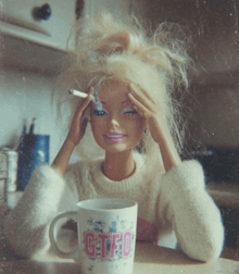 a barbie doll is smoking a cigarette next to a mug that says gfo