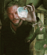a man with a beard is holding a piece of ice in his hand .